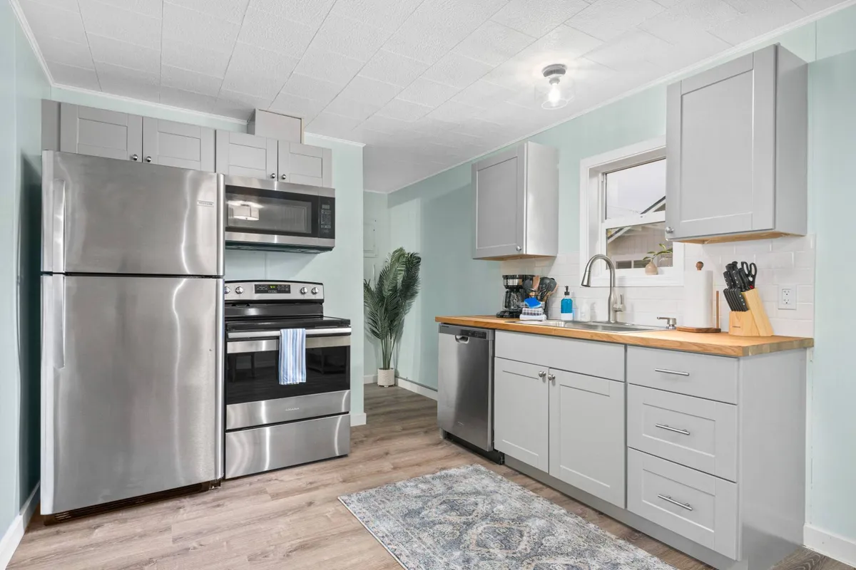 A modern, fully equipped kitchen featuring stainless steel appliances, a butcher block countertop, and a sunlit window. The space is ready for meal prep, baking, or entertaining, with an inviting and contemporary feel.
