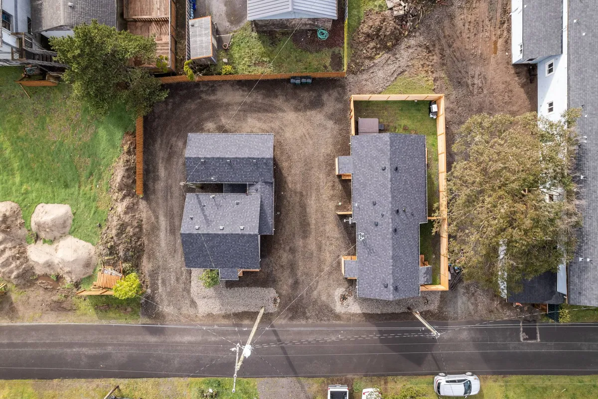 This exterior shot captures two houses surrounded by lush greenery and a gravel area, set up for outdoor gatherings and recreation. The space is tranquil and open, suggesting plenty of safe room for supervised pet play and family activities.