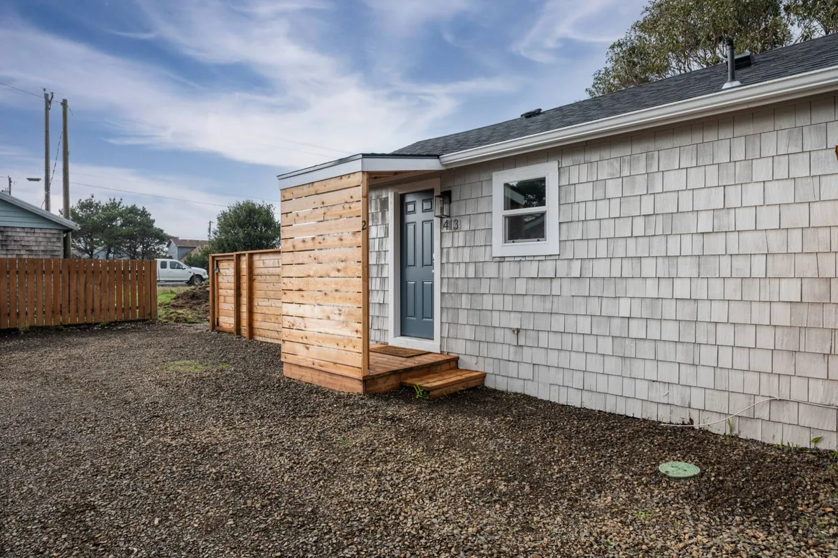 The photo highlights the front steps and shingle siding of the cottage, with an emphasis on enjoying outdoor activities like morning coffee or evening conversations on the porch. It gives a clear sense of the transition between indoor and outdoor living, perfect for relaxing with a pet.
