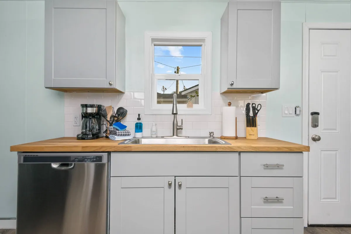 A cozy kitchen with wooden countertops, a coffee maker, and a view through the window. The natural light and open feel evoke a welcoming environment, inviting guests to enjoy a meal or a cup of coffee before heading out to explore the beach or nearby parks with their pet.